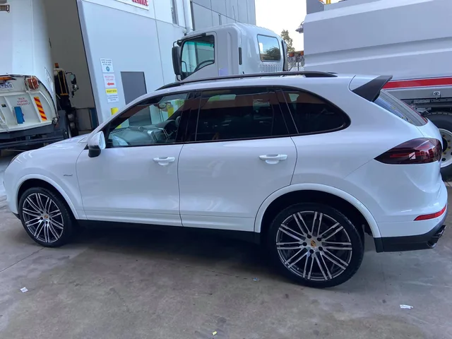 White Porsche Cayenne alongside the work van