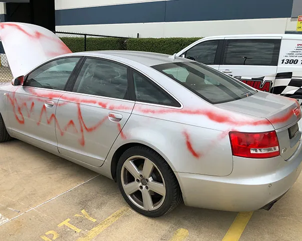 Silver Audi sprayed with red graffiti paint across the doors and boot