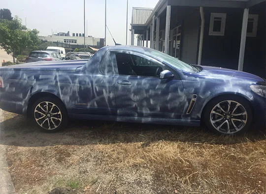 Blue Holden ute covered in industrial fallout speckling